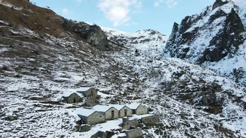 Drone flight in mountain with snow over old constructions (alpine pasture). 4K Stock Footage 148031491