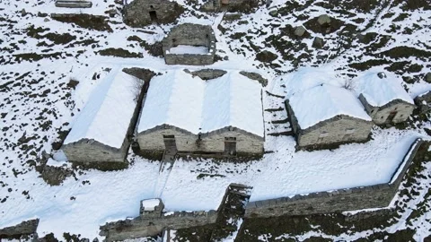 Drone flight in mountain with snow over old constructions (alpine pasture). 4K Stock Footage 148031494