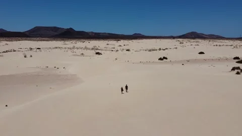Drone flight over 2 people walking through the dunes in Corralejo, Fuerteventura Video stock 286358524