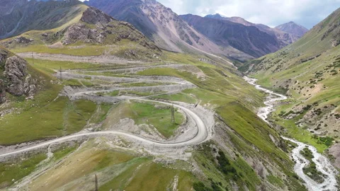 Drone flight over Barskoon Pass with winding road and mountain river. Stock Footage 315443086