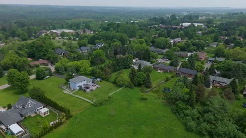 Drone flight over Caledon, Ontario showing leafy homes beside open meadow and Vídeo Stock 325832946
