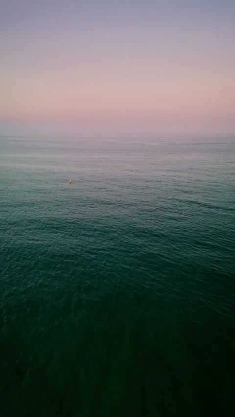 Drone flight over calm sea during pastel sunset Видео 311065486