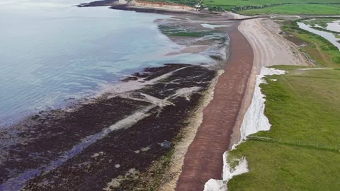Drone flight over coastal cliff edge revealing sandy beach, tidal reef Stock Footage 309764610