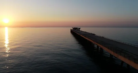 Drone flight over final abandoned harbor dock bridge in an orange sunrise Stock Footage 124179749