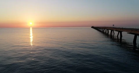 Drone flight over final abandoned harbor dock bridge in an orange sunrise Stock Footage 124218230