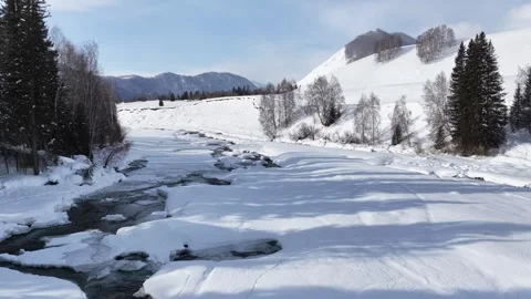 Drone flight over frozen river valley and snowy forest in Xinjiang Stock Footage 336609492
