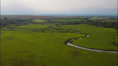 Drone flight over a green meadow, river and sunset Stock Footage 277227935