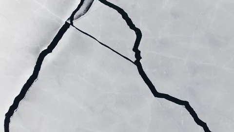 Drone flight over intricate pattern of cracks on the icy surface of frozen lake Stock Footage 310529106