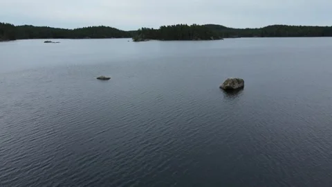 Drone flight over a lake with a focus on two small rocks in Sweden. Stock Footage 248098813