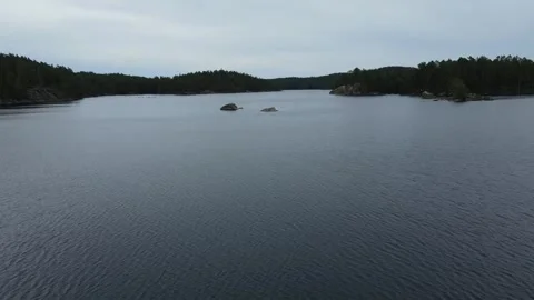 Drone flight over a lake with two small rocks in Sweden. Stock Footage 248098950