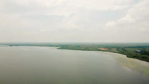 Drone flight over a large lake towards agricultural fields in plain countryside 動画素材 263310727
