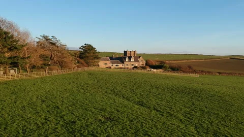 Drone flight over a lush green meadow with a view of a farm with old buildings. Stock Footage 163036026
