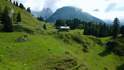 Drone flight over mountain valley with trekking path, cabin, and rocky terrain Stock Footage 314199025