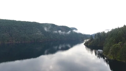 Drone flight over narrow stretch of lake surrounded by pine forest Video stock 126981601