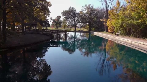 Drone flight over reflective pond in fall with sun flares Stock Footage 134950088
