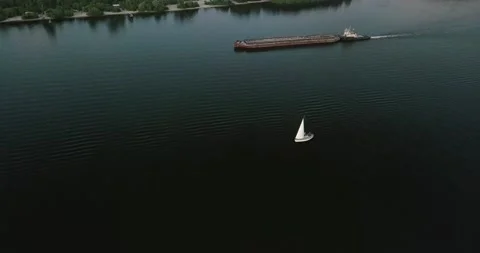 Drone flight over the river overlooking the tug barge and sailboat in the Stock Footage 136513353
