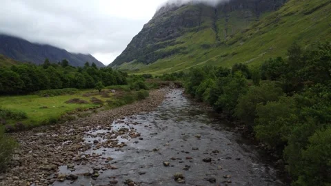 Drone flight over river rising towards hill in Glencoe, 4K Stockbeeldmateriaal 319490039