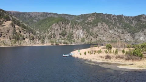 Drone flight over a river with a shore and a jetty on a sunny day Video stock 199040816