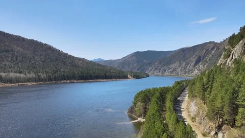 Drone flight over a river with a shore and a road on a sunny day Video stock 199041357