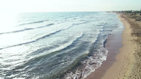 Drone flight over a sandy beach, calm waves, deserted beach Stock Footage 306872691