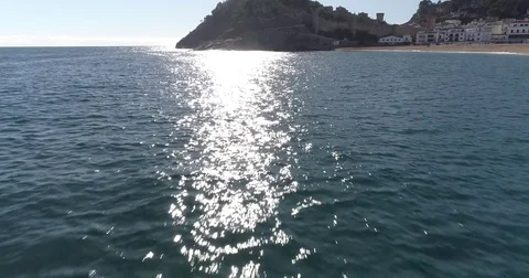 Drone flight over the sea towards castle on hill beside the water Stock Footage 85357069