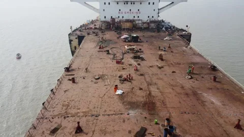 Drone Flight Over Shipbreaking Yard with Workers on Dismantled Cargo Ship Stock Footage 327167633