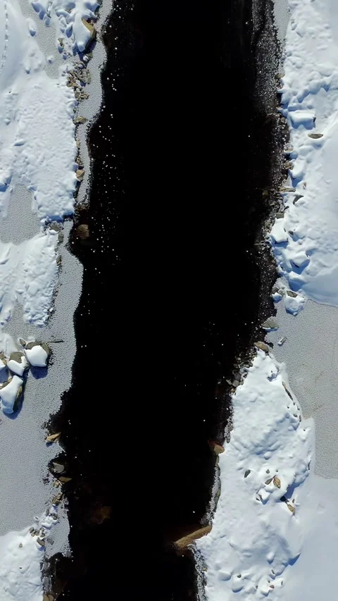 Drone flight over snow and black water creek. Norway Stock-Footage 319477144