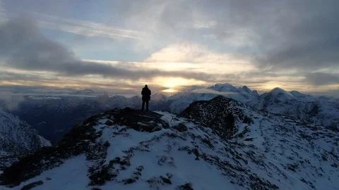 Drone flight over snow capped mountains with a person standing on the top 스톡 동영상 100585870