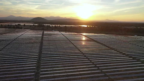 Drone flight over solar power plant moving to left with sunset and mountains Stock Footage 160932098