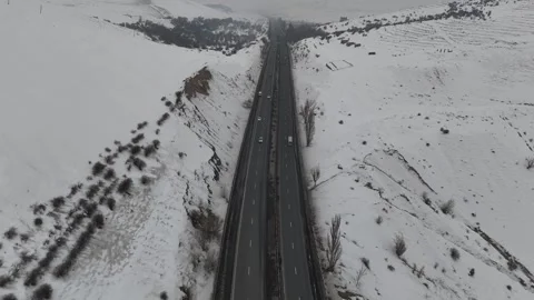 Drone flight over a straight winter highway through snowy hills. Video stock 328006334
