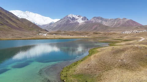 Drone flight over Tulpar-Kul Lake with yurts and Lenin Peak in the background. Stock Footage 321397111