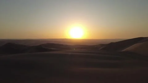 Drone flight over a vast desert landscape at sunset with rolling sand dunes.. Stock Footage 327756226