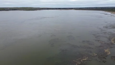 Drone flight over a vast, moody lake towards the horizon on a cloudy day Stock Footage 312416572