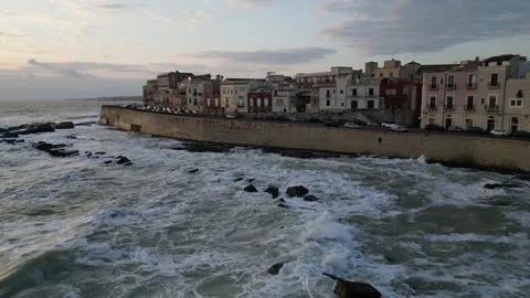 Drone flight over waves towards houses in Syracuse, Italy Stock Footage 345044913