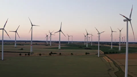 Drone flight to the right over a large field with many wind turbines spinning. Stock Footage 163100269
