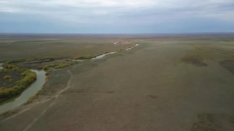 Drone flight rising along dirt road revealing wide Kazakh steppe Stock Footage 334329954