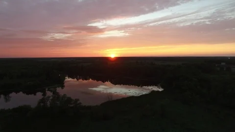 Drone in flight shows pretty sun rise with coloured clouds with pond - 24fps Stock Footage 104104640
