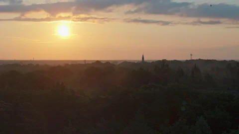 Drone flight at sunrise over a forest with city towers and chimneys on the .. Video stock 285021681