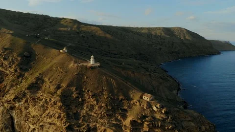 Drone flight at sunset over the lighthouse, surrounded by turquoise green sea Video stock 123173624