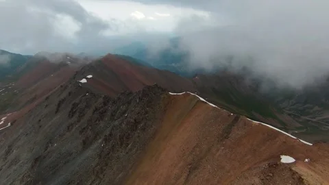 Drone flight through clouds above a rugged mountain ridge in Kazakhstan Stock Footage 340423142