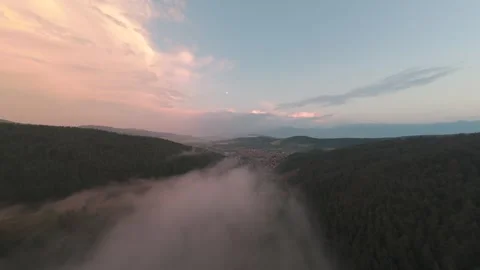 Drone flight through fog revealing Belitsa mountain town at sunset in Bulgaria. Stock Footage 343686181