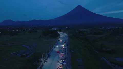 Drone flight toward Mayon Volcano above illuminated bypass road. Stock Footage 336908787