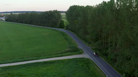 Drone flight tracking a car on a German country road. You can see green meadows Stock Footage 163088847