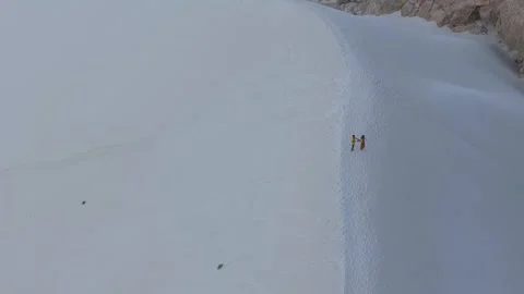 Drone flight, two people climb a steep sand dune with the turquoise sea, Socotra Stock Footage 317583254