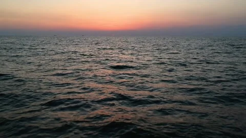 Drone Fly backward over Ocean surface during sunset and reflection of sunset. Stock Footage 130935793
