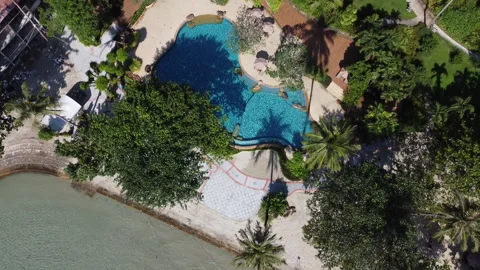 A drone fly over a bright blue swimming pool overlooking  Video stock 174207744