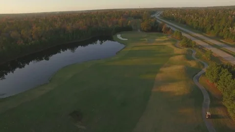 Drone fly over golf course with golf cart below at sunset 库存影片 78714125