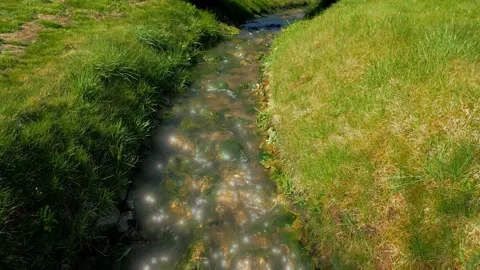 Drone fly over of a stream with exaggerated light reflection effect Video stock 238992939