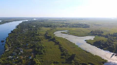 Drone fly over waving river of blue color surrounded by local village with va 写真素材