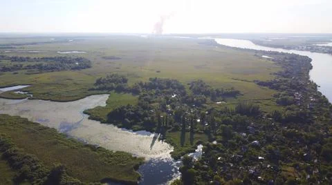 Drone fly over waving river of blue color surrounded by local village with va Stock Photos